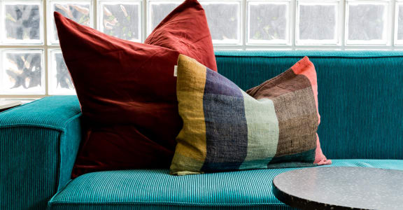 a blue couch with pillows in front of a glass wall