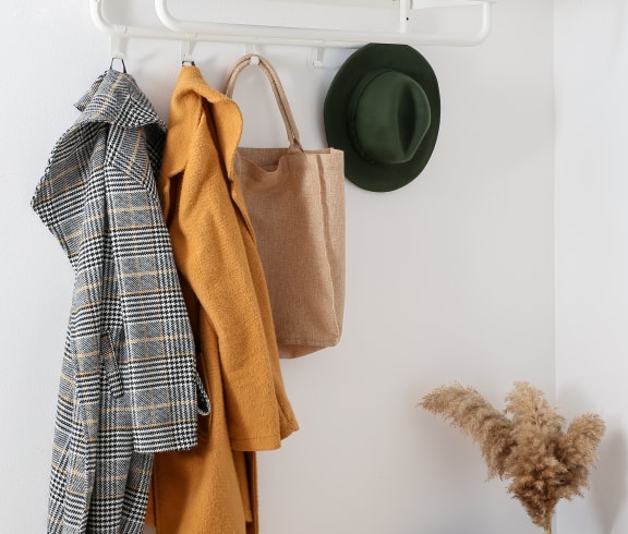 a white shelf with clothes and a hat hanging on it