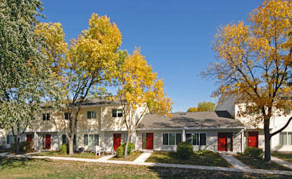 A row of houses with trees in front of them.
