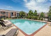 Thumbnail 14 of 26 - A swimming pool surrounded by lounge chairs and a fence.