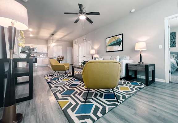 A living room with a yellow chair and a rug with a geometric pattern.