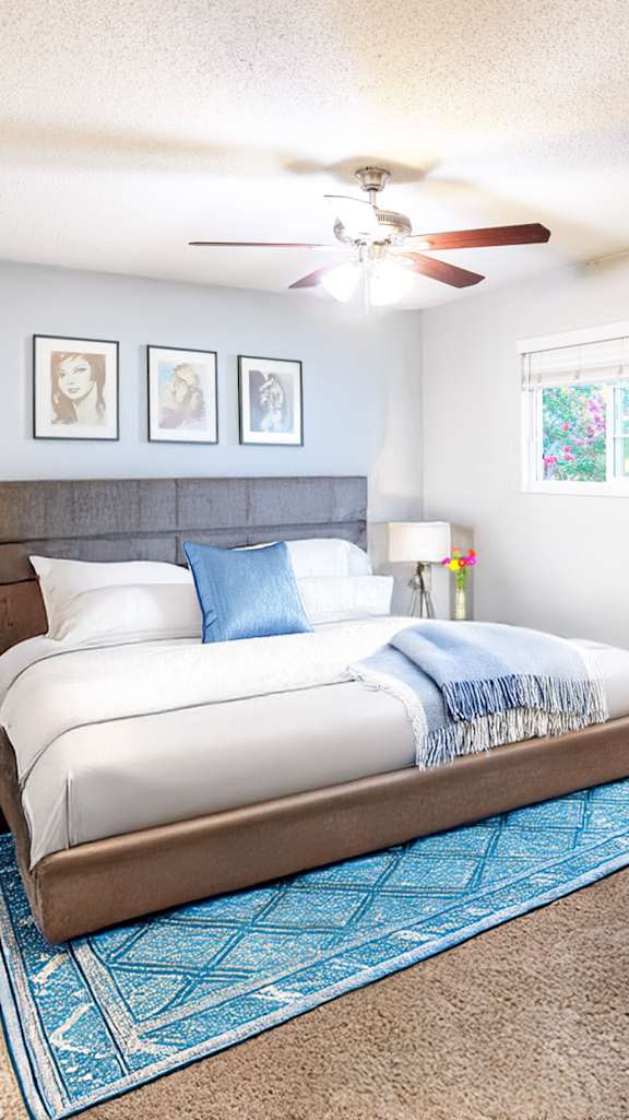 A bedroom with a bed, a chair, and a ceiling fan.