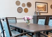 Thumbnail 6 of 7 - A dining table with chairs and a vase of flowers on it.