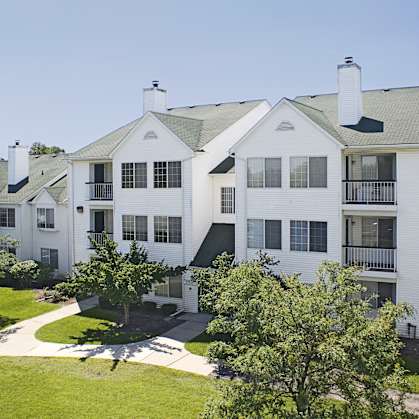 an aerial view of an apartment building with green grass and trees at Village Club on Franklin, Southfield Michigan