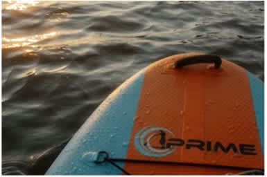 A close up of a blue and orange surfboard with the word "PRIME" written on it.