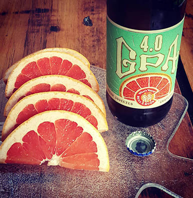A 4.0 IPA beer next to sliced grapefruit.