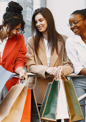 Two women are walking down the street with shopping bags.