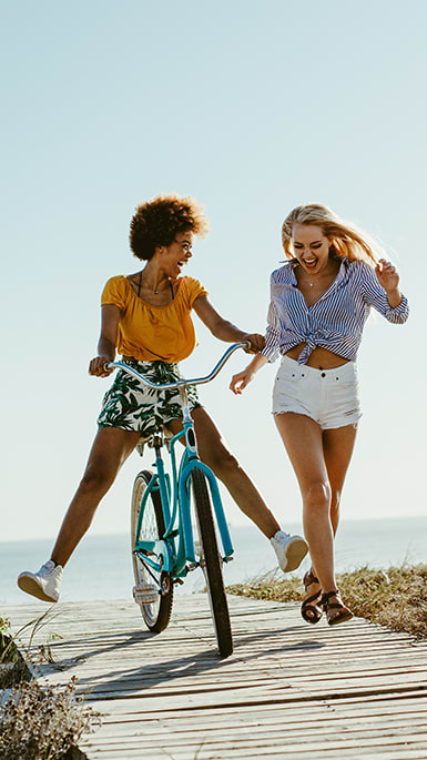 two women walking and riding a bike on a boardwalk at Indian Trace, West Palm Beach, FL