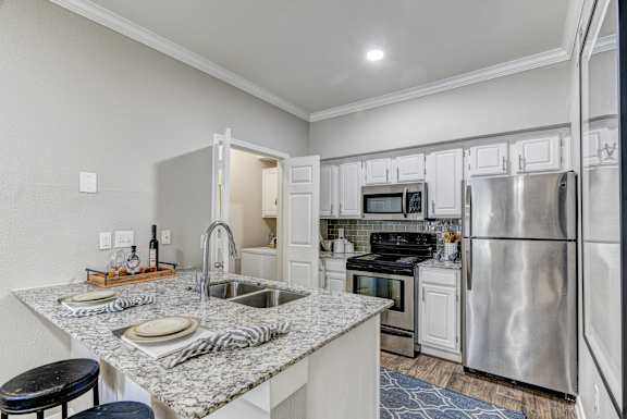 A kitchen with a granite countertop and stainless steel appliances.