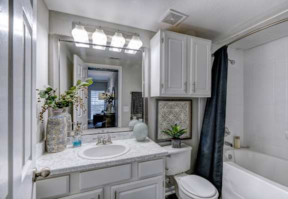 A bathroom with a white tub, sink, and toilet.