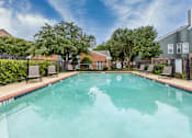 Thumbnail 15 of 26 - A swimming pool surrounded by trees and buildings.