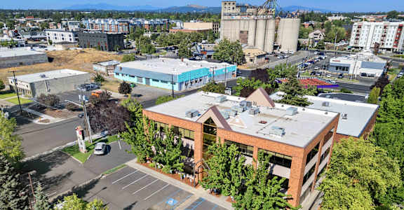 an aerial view of a brick building with a parking lot and other buildings