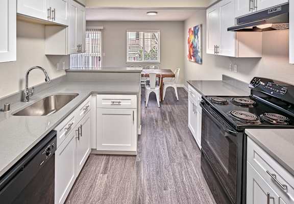 a kitchen with white cabinets and appliances and a dining room with a table at Arterra Apartments, Kent, 98030