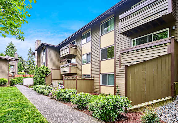A residential building with a well-maintained lawn and a clear sky.