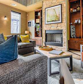 A living room with a grey couch and a fireplace.