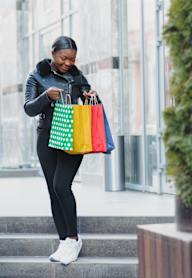 A woman is walking down the stairs with a colorful shopping bag in her hand.