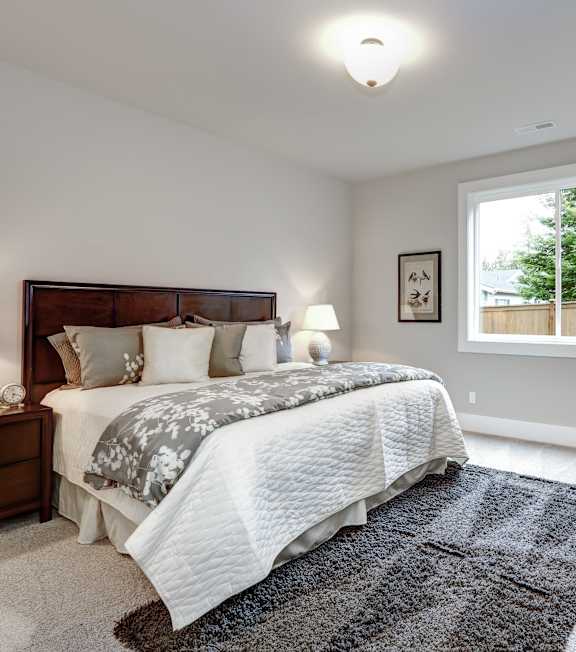 A bedroom with a large bed and a chair.
