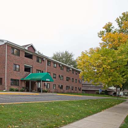 A red brick building with a green awning and an American flag on the roof.