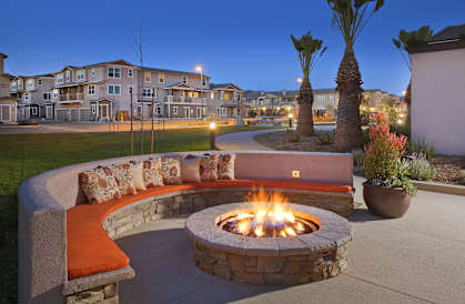 an outdoor fire pit at night with an apartment building in the background