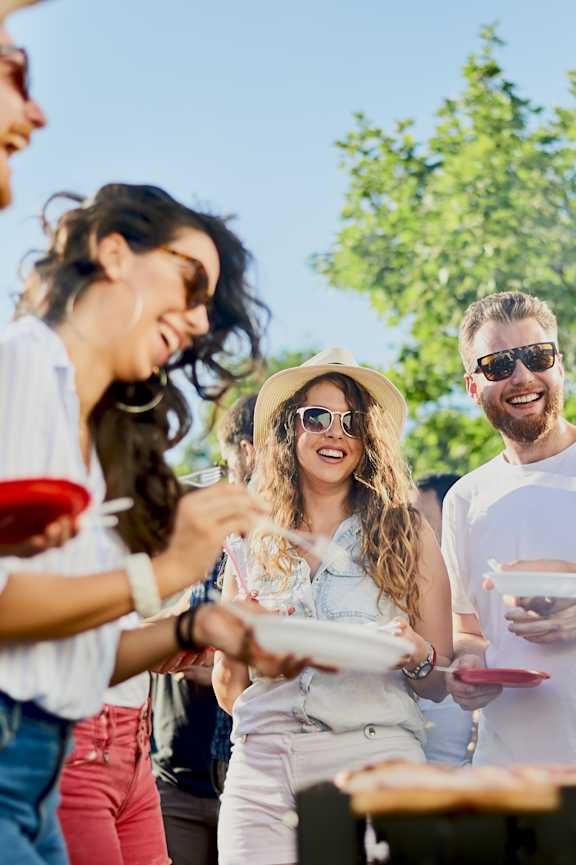 A group of people are gathered around a table, enjoying food and drinks.