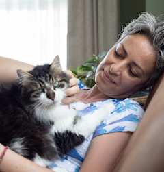 A woman is cuddling with a cat on a couch.