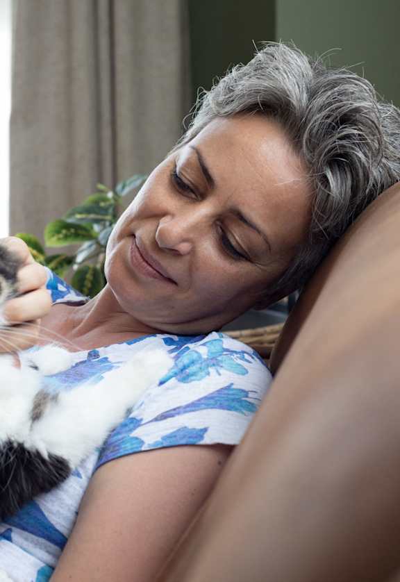 A woman is cuddling with a cat on a couch.