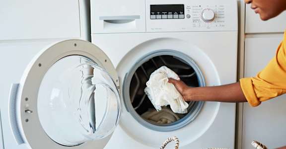 a person putting a cloth into a washing machine at Hamilton Manor Apartments, Hyattsville, 20782