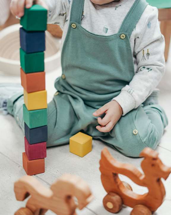 A child playing with wooden blocks and a toy horse.