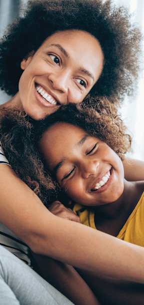 A woman with a child on her lap, both are smiling.
