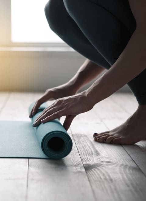 a person rolls up a yoga mat on a wooden floor at 808 Berry Place, Minnesota, 55114