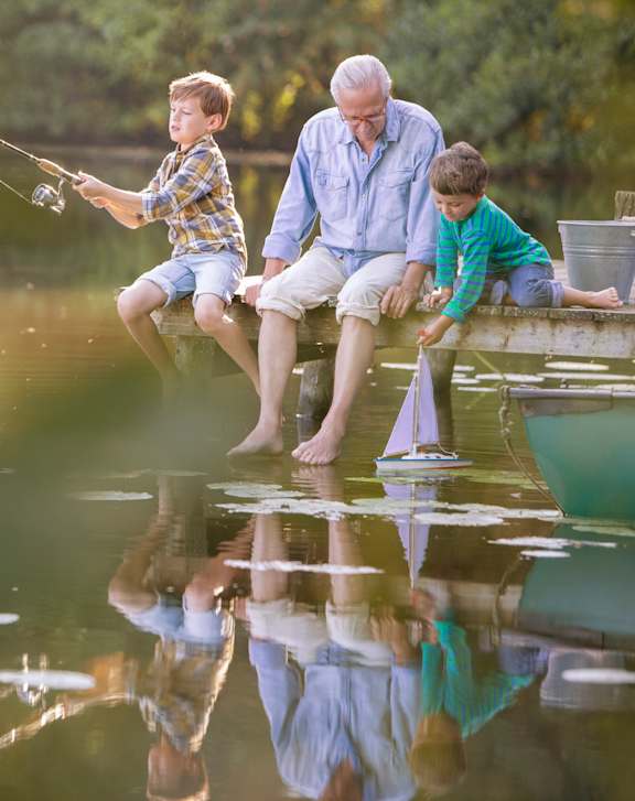 a grandfather and two grandchildren fishing on a dock