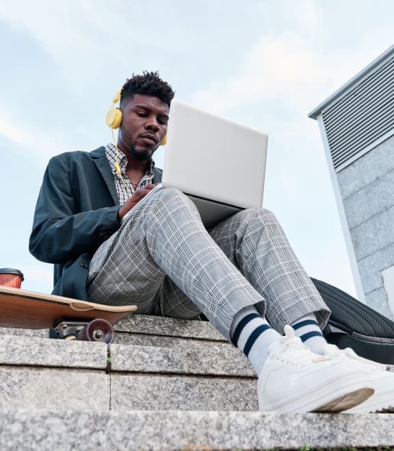 a man sitting on the stairs with a laptop and headphones on at Residences at Manchester Place, Manchester