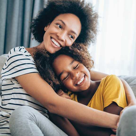 A woman with a child on her lap, both are smiling.