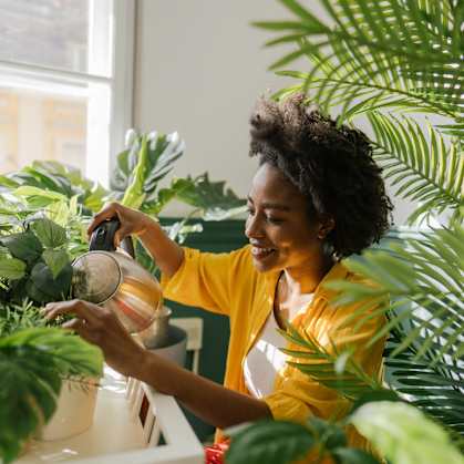 a woman watering her plants with a watering can at Cityscape, St Louis Park, MN, 55416