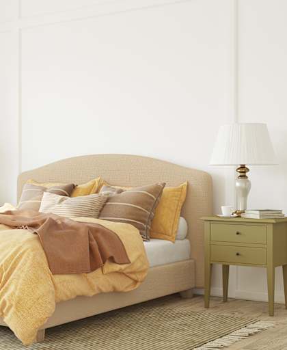 A bed with a yellow comforter and a green side table.
