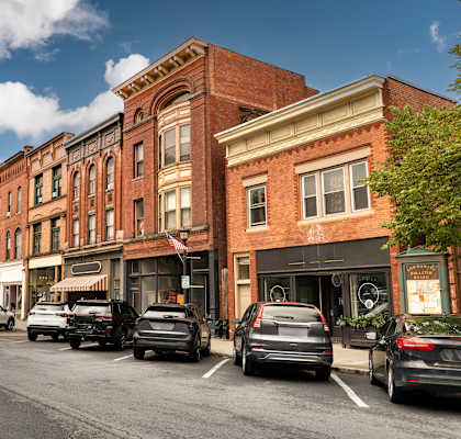 Cars parked on the side of a street in front of a row of buildings.
