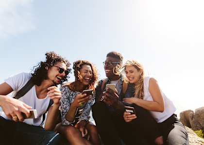 a group of friends sitting on a rock looking at their cell phonesat The Hub at 934 Apartments, Georgia, 30349