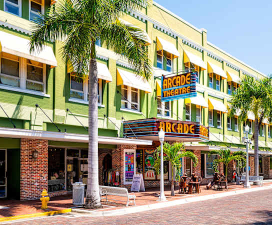a row of green and yellow buildings with palm trees in front of them at Bay Harbor, Fort Myers, FL, 33919