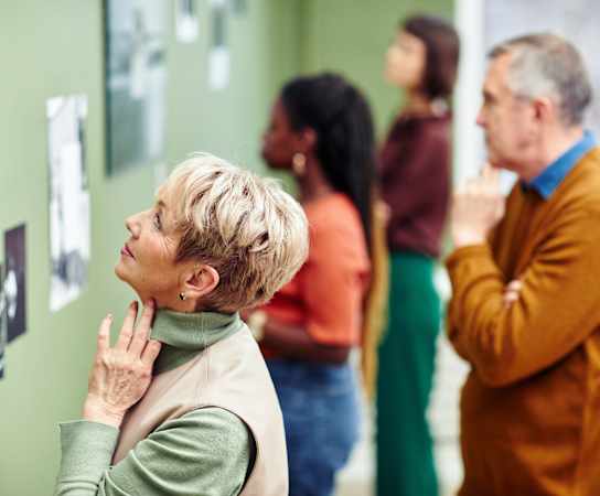 an older woman looking at photographs on the wall of a museum at Thornberry Apartments, Charlotte North Carolina