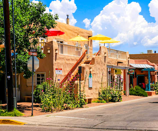 a small town street with buildings and umbrellas at Arterra, New Mexico