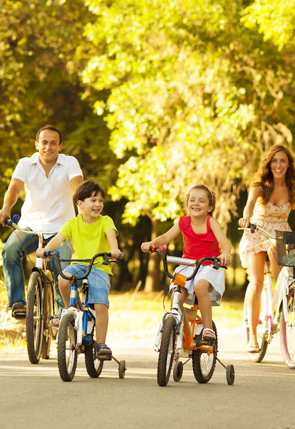 A family of four riding bikes together on a path.