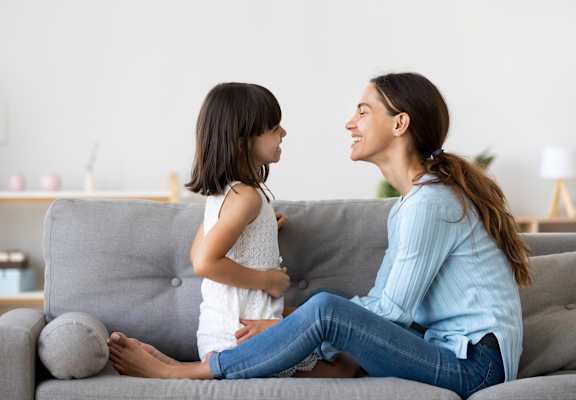 a mother and daughter sit on a couch and look at each other at King West One, Billings, 59106
