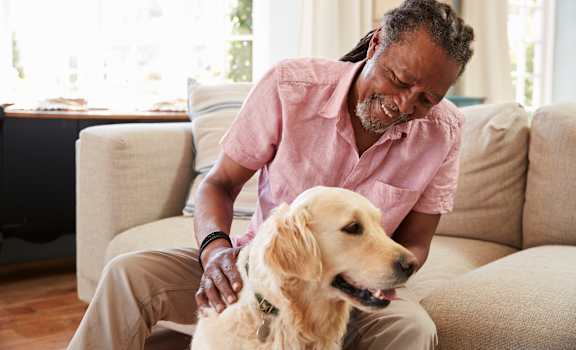 a man sitting on a couch petting a dog at Emblem Alpharetta, Alpharetta, GA, 30009