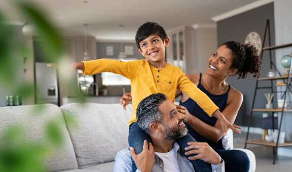 a young boy sitting on top of his parents in a living room