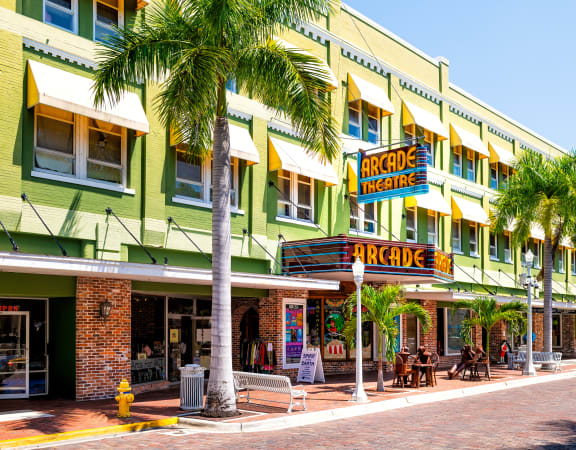 a row of green and yellow buildings with palm trees in front of them
