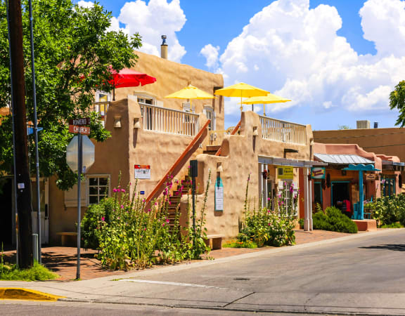a small town street with buildings and umbrellas at Arterra, New Mexico