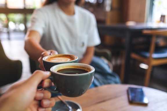 A person is holding a cup of coffee with a latte art on top.