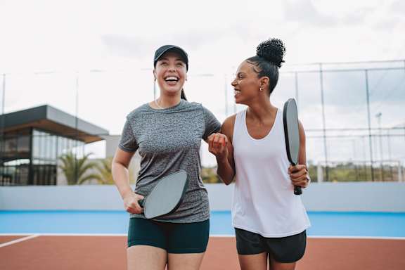 Two women are standing on a tennis court holding tennis rackets.