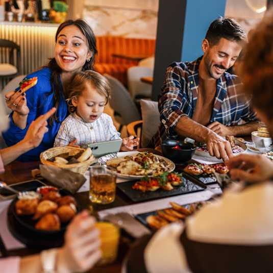 A group of people are gathered around a table enjoying a meal together.