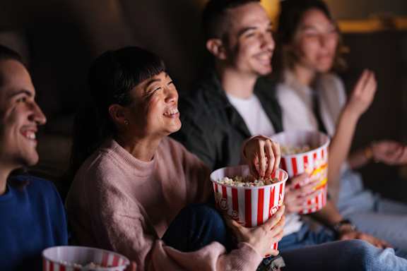 A group of people are sitting together and eating popcorn.